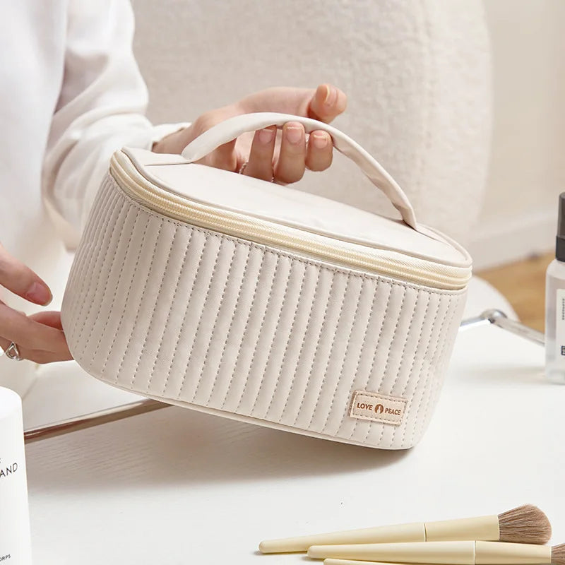 grande trousse de toilette matelassée porter à la main par une mannequin