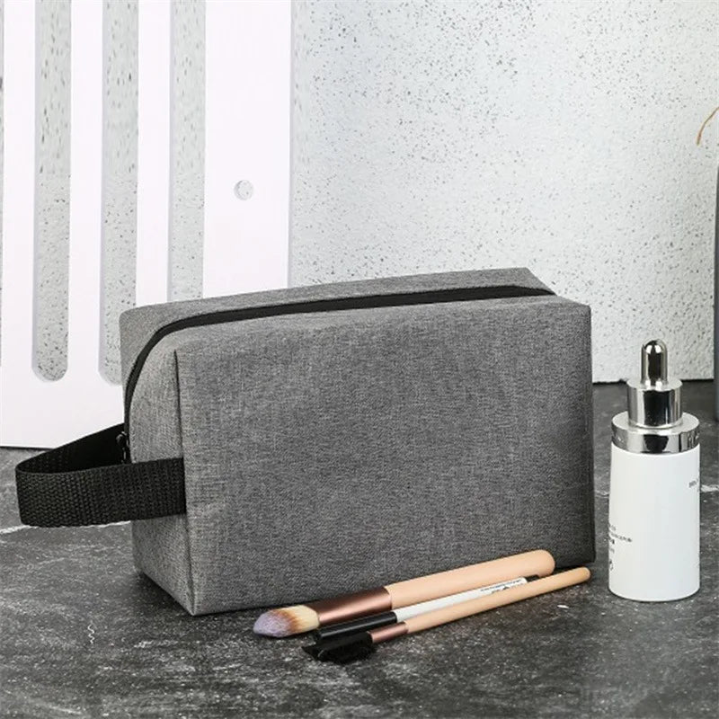 trousse de toilette petite pour homme grise posé sur une table