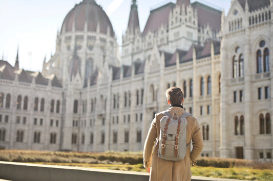 homme portant un sac à dos tendance devant un chateau