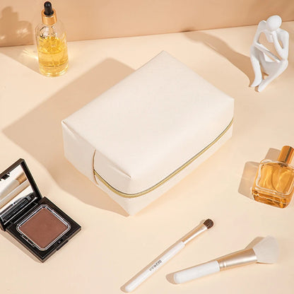 trousse de toilette xxl pour femme beige posée sur une table